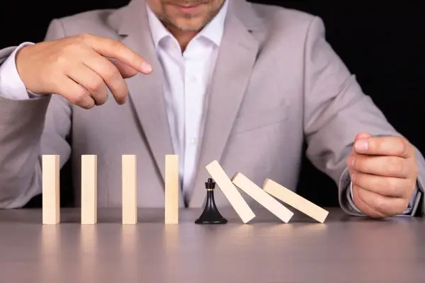 A chess pawn stops a wooden domino from falling - this is the effect of a continuous fall or risk, strategy and concept of successful intervention for a business. como-prevenir-riesgo-reputacional